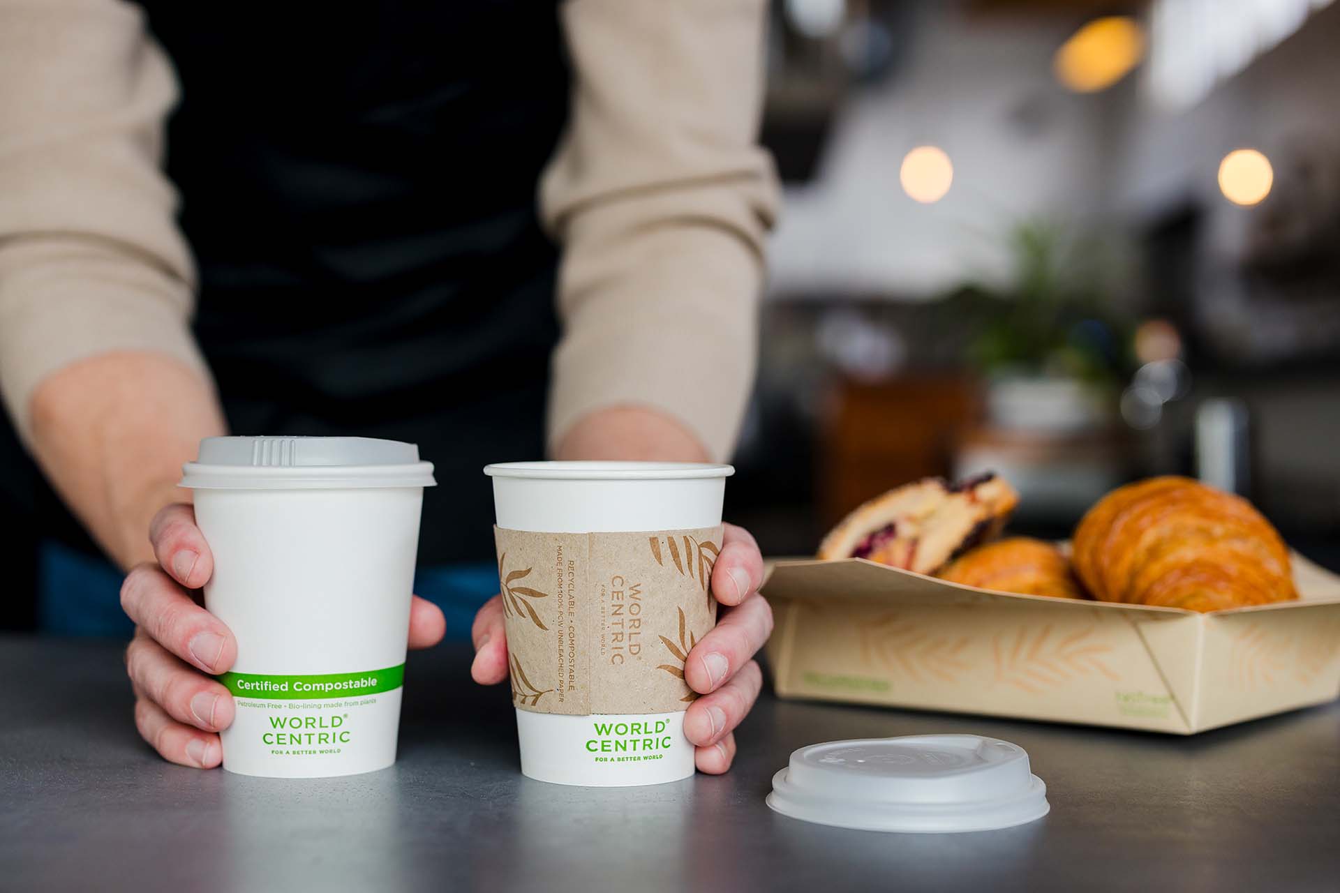 A server places World Centric compostable cups on a counter.