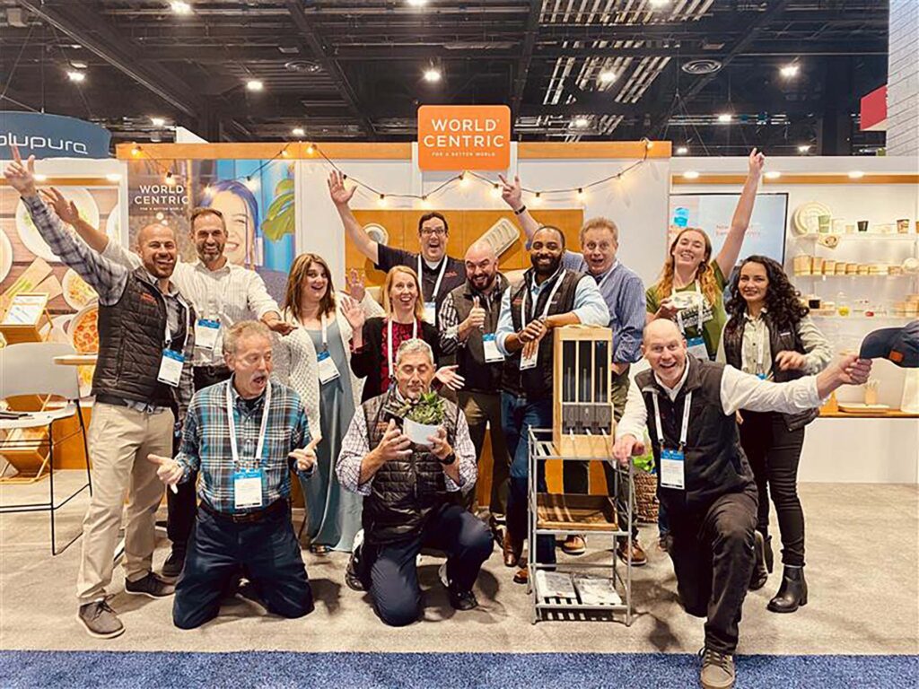 World Centric staff striking joyous poses at their tradeshow booth